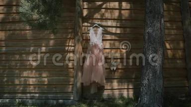婚纱挂在户外。白色婚纱挂在木屋上，风吹着裙子。